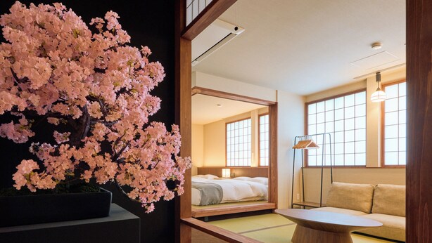 A traditional Japanese-style room with a bed, sofa, and a large cherry blossom tree. - KONJAKUSO Osaka Tempozan KANOH  SHOHAKU (Osaka)