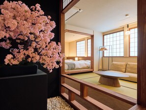A traditional Japanese-style room with a bed, sofa, and a large cherry blossom tree. - KONJAKUSO Osaka Tempozan KANOH  SHOHAKU (Osaka)
