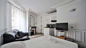 Ein Hotelzimmer mit einem großen Bett, einem schwarzen Ledersofa, einem Fernseher, einer Küchenzeile und einem Kamin.