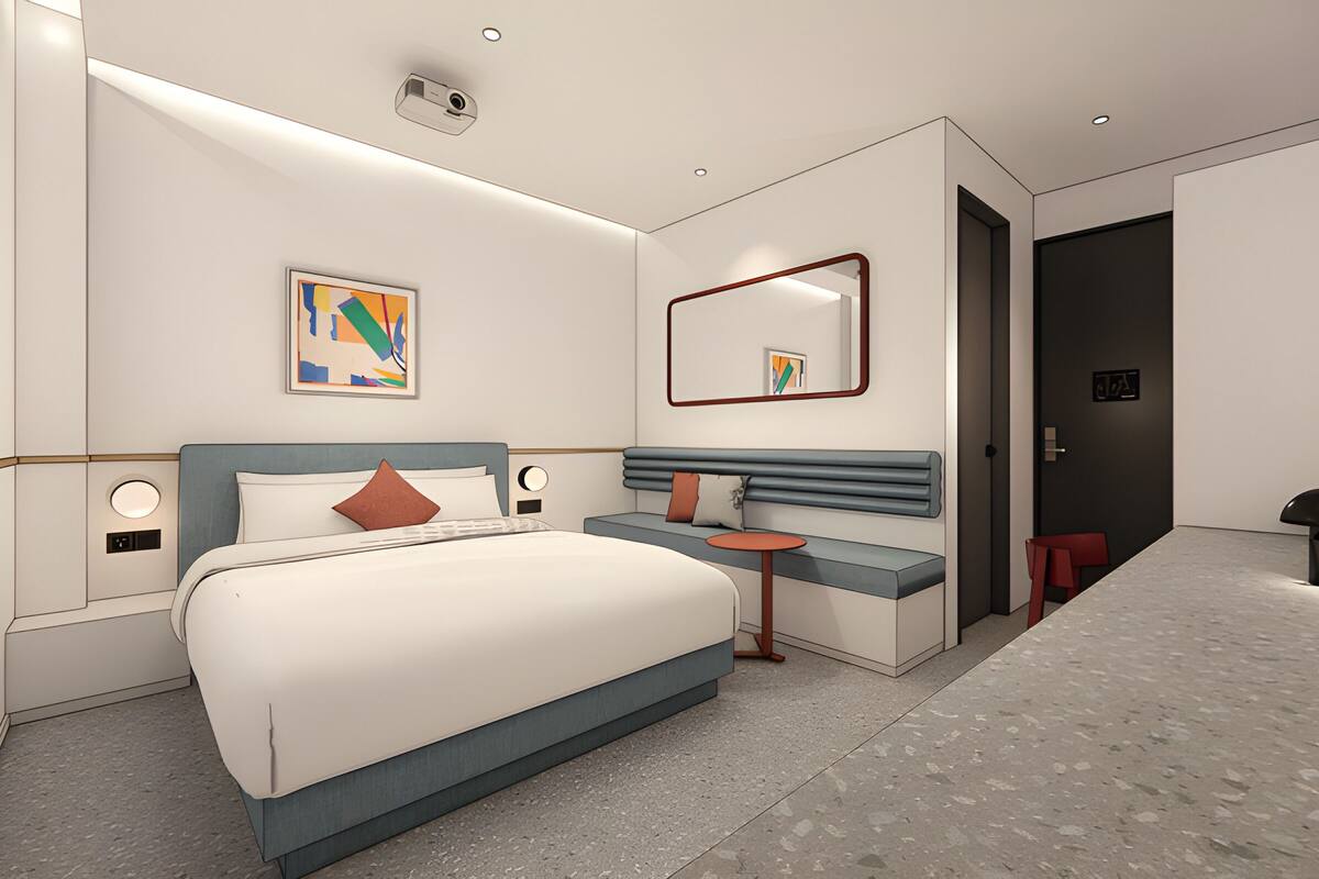 Een moderne hotelkamer met een groot bed, nachtkastjes, een klein rond tafeltje, een spiegel en een deur naar de badkamer.
