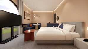 Une chambre d’hôtel moderne avec un grand lit, un coin salon, une petite table et un téléviseur.