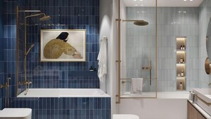 Une salle de bain moderne avec une grande baignoire, un espace douche séparé et des toilettes. Un tableau encadré est accroché au mur, au-dessus de la baignoire.