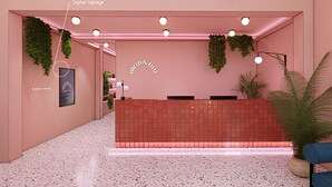 Un espace d’accueil avec un mur rose, un comptoir d’accueil rouge et des plantes suspendues.