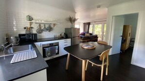 Een moderne keuken met witte metrotegels, een zwart aanrechtblad en een eetgedeelte met een tafel en stoelen.