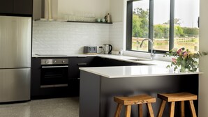 Een moderne keuken met een groot raam, een inbouwoven, een koelkast en een koffiezetapparaat.