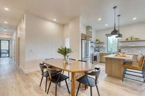 Une cuisine moderne dotée d’un îlot central, d’appareils électroménagers intégrés et d’un coin repas avec une table et des chaises en bois.