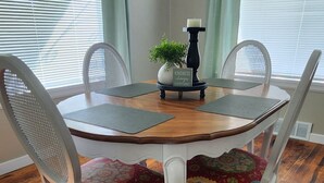 A dining area with a round wooden table, white chairs, and a chandelier. - OldCharm Spacious 2bdrmhouse in perfect location in Burley with WiFi,Central Air (Burley)
