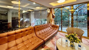 A modern interior with a leather sofa, a round table with water bottles, and large windows offering a view of the outside. - Check Inn Homes - Rishikesh (Rishikesh)