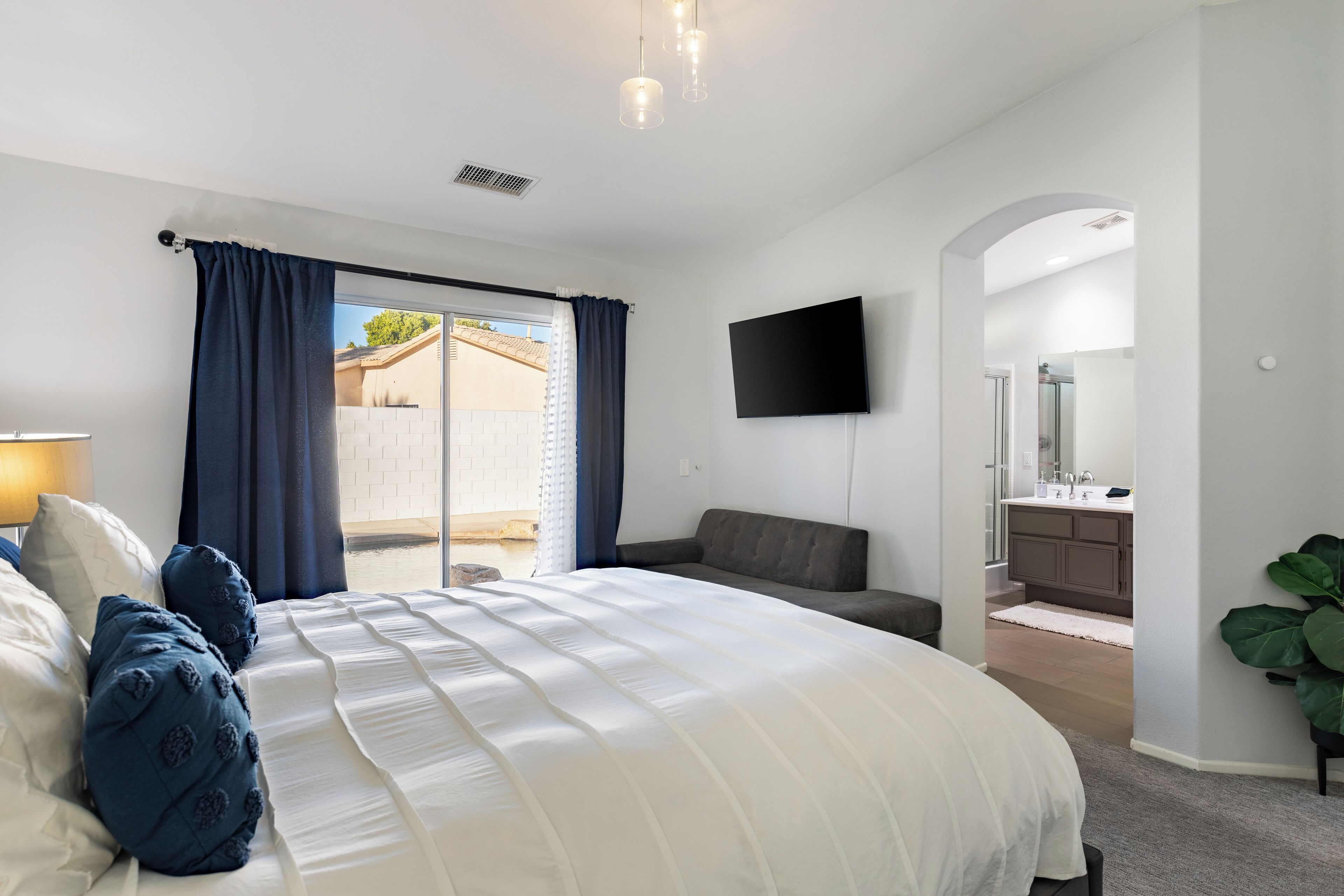 Un dormitorio con una cama grande, un televisor montado en la pared y vistas al exterior.