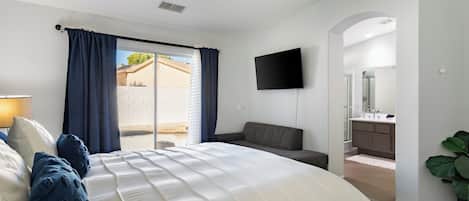 Un dormitorio con una cama grande, un televisor montado en la pared y vistas al exterior.