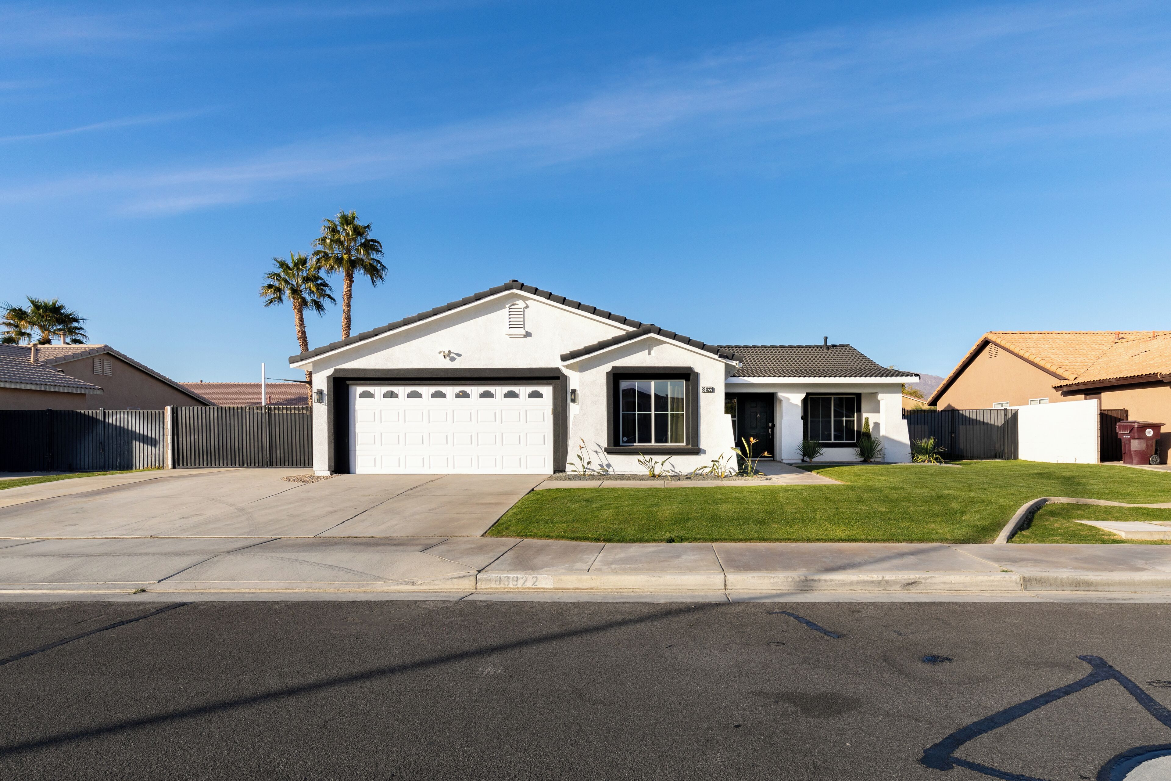 A residential house with a garage, a well-maintained lawn, and a clear blue sky.