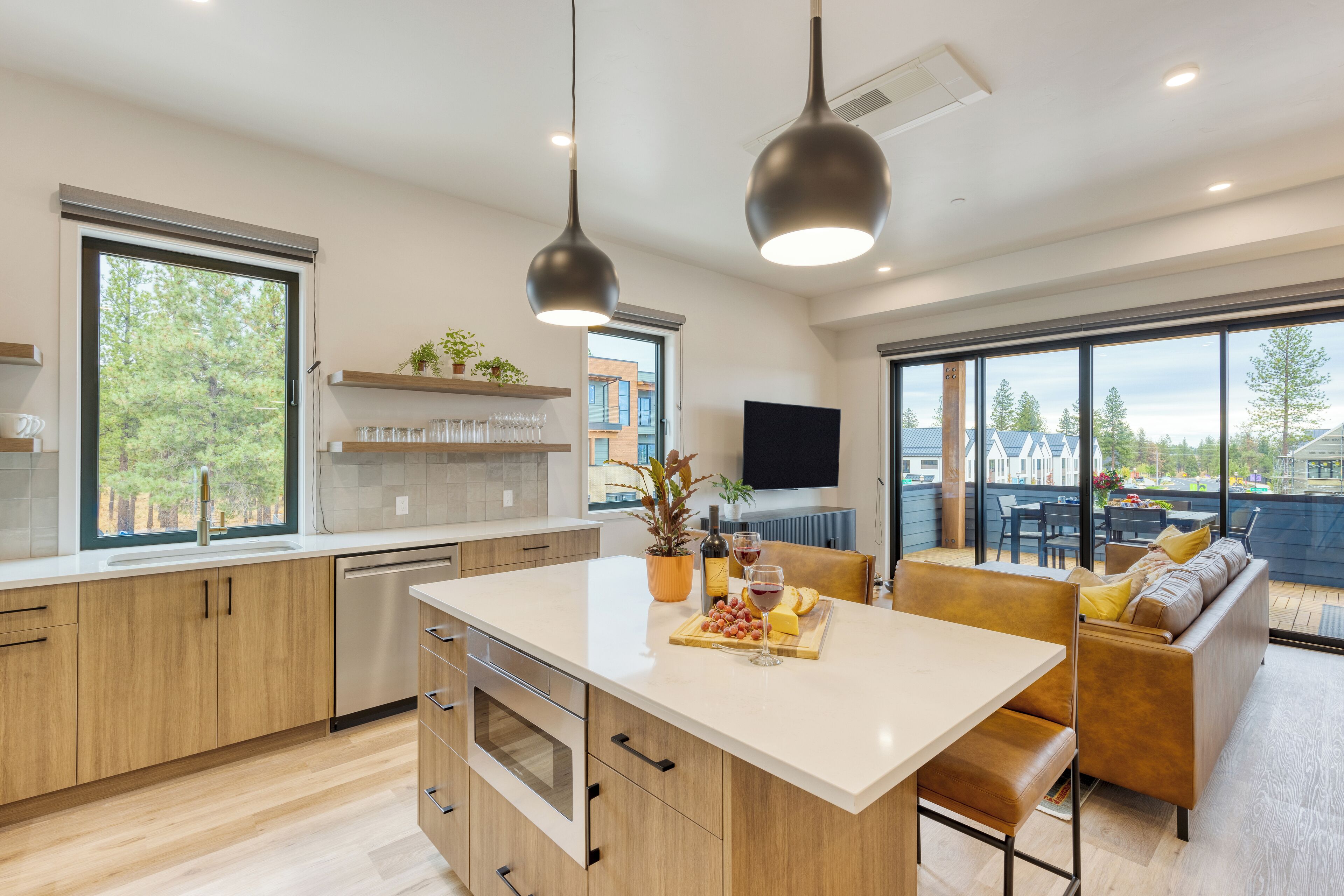 A modern kitchen with a large island, wooden cabinets, and a dining area with a sofa and table.