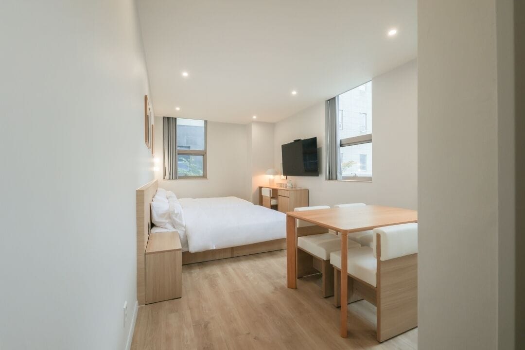 Ein modernes, kompaktes Zimmer mit Bett, Schreibtisch und Fernseher.