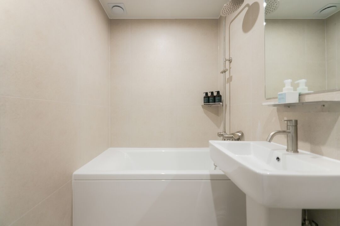 A modern bathroom with a white bathtub, a sink, and a mirror.