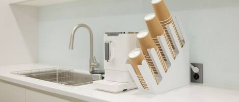 A modern kitchen with a built-in coffee machine, a sink, and a paper towel dispenser.