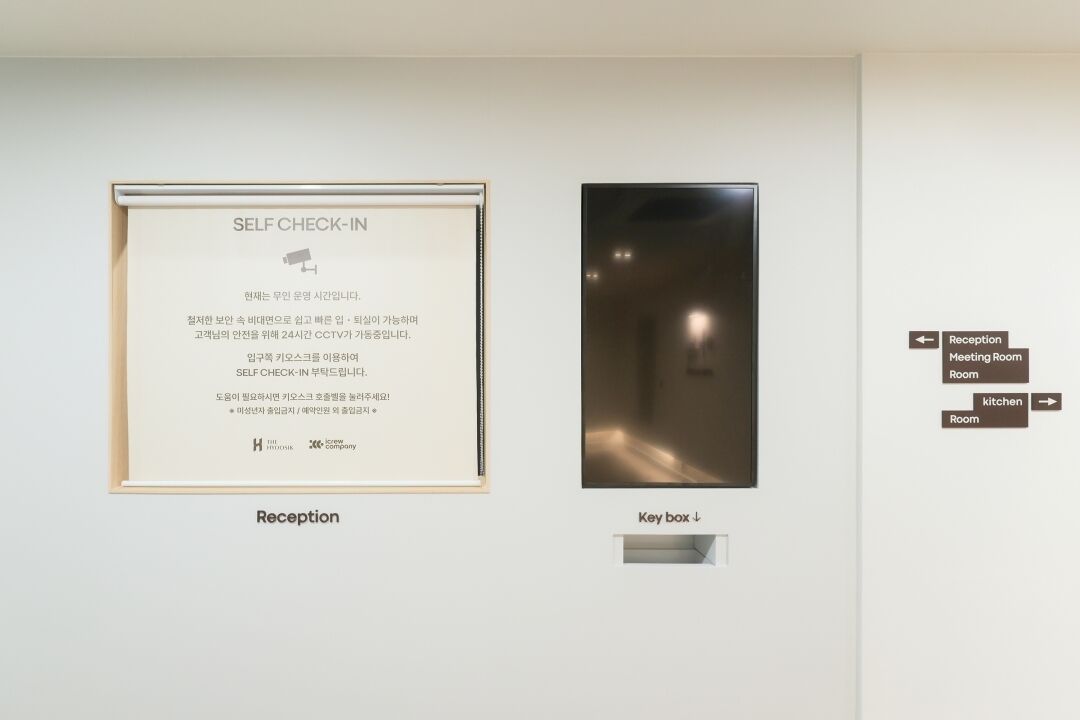 A framed 'Self Check-In' sign and a key box in a hotel reception area.