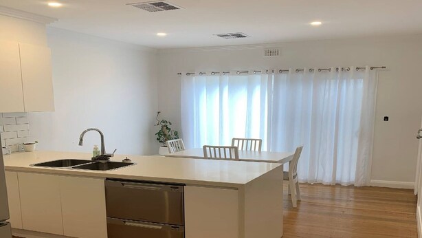 A modern kitchen with a central island, stainless steel appliances, and a dining area with a table and chairs.