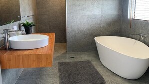 A modern bathroom with a freestanding bathtub, a wooden vanity with a sink, and a large mirror.