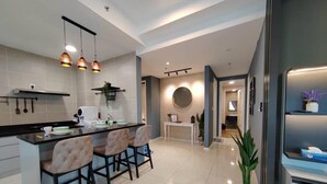 A modern kitchen with a central island, pendant lighting, and a view into the living area. - IPOH Sunway Onsen Suites by uBook (Ipoh)