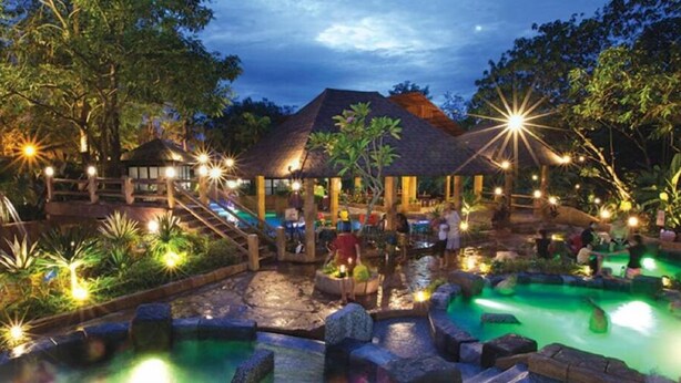 A resort with a pool area, wooden structures, and a thatched-roof building. - IPOH Sunway Onsen Suites by uBook (Ipoh)
