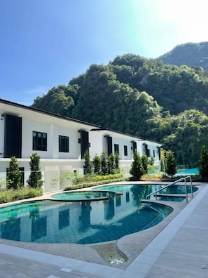 A modern hotel with a pool and a mountain backdrop.