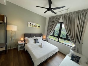 A hotel room with a bed, bedside lamps, a ceiling fan, a window with curtains, and artwork on the wall.