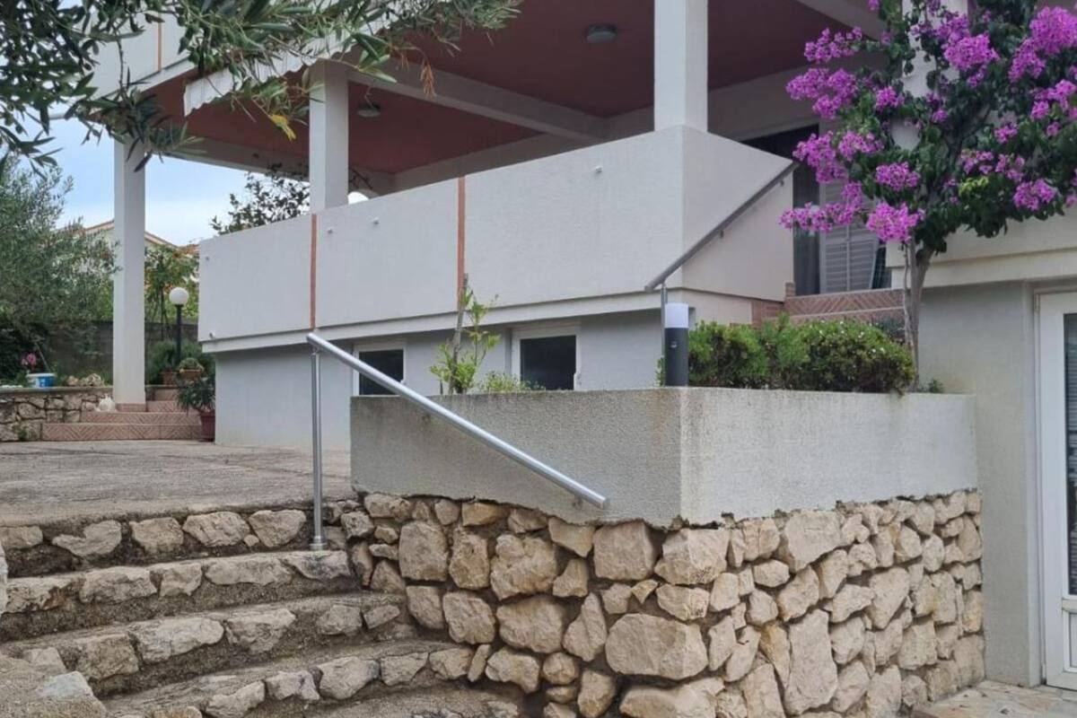Un escalier en pierre mène à un bâtiment moderne doté d’un balcon.