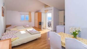 A bedroom with a bed, a desk, and a chair. There is a window and a door leading to a balcony. - Apartments Cihorich (Dugi Rat)