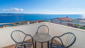 A balcony with a table and chairs overlooking a coastal view. - Apartments Cihorich (Dugi Rat)