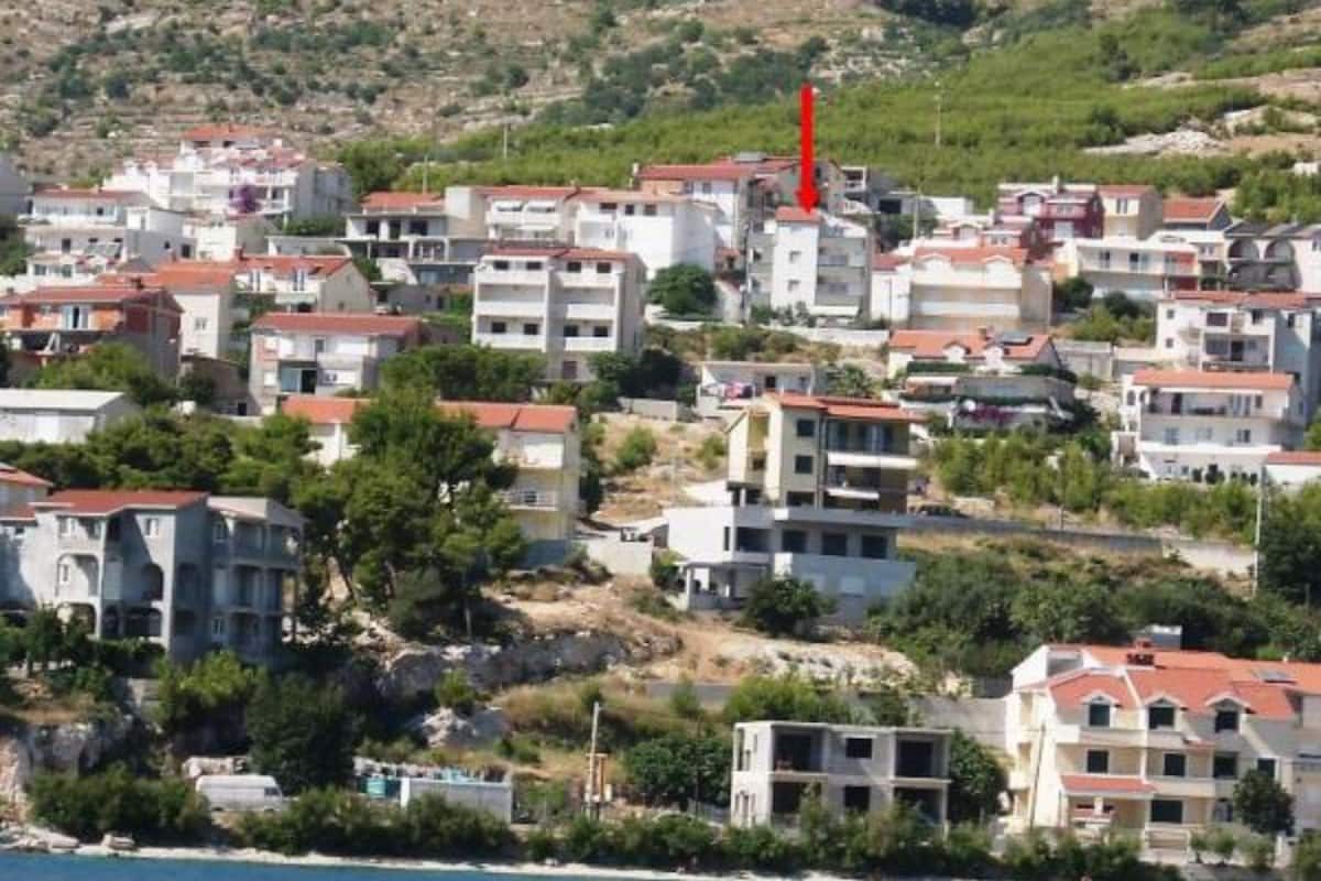 A coastal residential area with multiple two-story buildings, some with balconies, and a hillside in the background.
