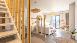 Et moderne interiør med trappe, bambusudsmykning, sofa og hængegyngestol.
