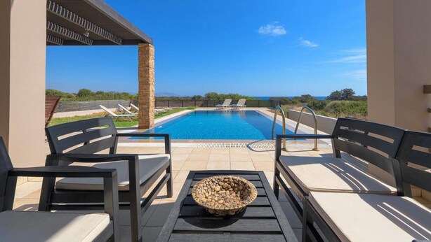 A poolside area with lounge chairs, a fire pit, and a clear view of the pool and landscape. - Villa Blue Wave Tria (Rhodes)
