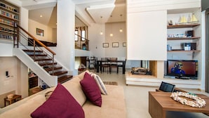 A spacious living area with a staircase, a dining area, and a TV. - Villa Blue Wave Tria (Rhodes)