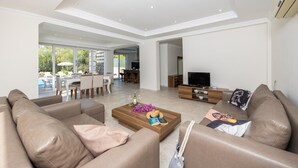 A spacious living room with a modern design, featuring a large sofa set, a wooden coffee table, and a flat-screen TV. - Four Seasons Villa in Oludeniz (Fethiye)