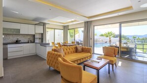Une chambre d’hôtel moderne dotée d’une cuisine, d’un canapé, d’un coin repas et d’un balcon avec vue.