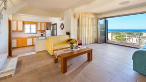 A spacious living area with a sofa, a wooden coffee table, and a kitchen in the background. - Villa Elena in Kalathos (Rhodes)