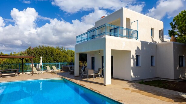 A modern two-story house with a swimming pool, outdoor seating, and a blue balcony railing. - Villa Apollonas in Peyia (Pegeia)