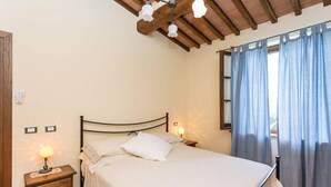 A bedroom with a bed, bedside tables, a lamp, and a window with curtains.