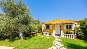 A yellow house with a tiled roof, a white door, and a small porch with a railing. - Villa Memi in Spartia (Kefalonia)