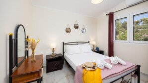 A bedroom with a bed, bedside table, nightstand, mirror, and wall decorations. - Villa Memi in Spartia (Kefalonia)