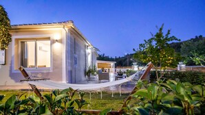 Una casa moderna con patio, que incluye una hamaca y mobiliario exterior.