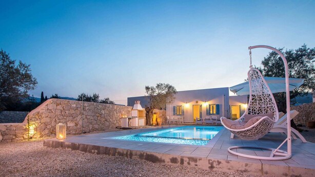 A modern house with a swimming pool, stone walls, and a hanging chair. - Villa Kalathos Dream White (Rhodes)