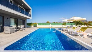 Un espace piscine moderne avec des chaises longues et un ensemble de mobilier de jardin.