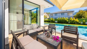A modern outdoor patio with a pool, seating, and a table set for two. - Villa White Cloud in Dalyan (Ortaca)