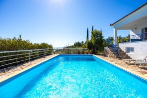 A rectangular swimming pool with clear blue water, surrounded by a stone deck and metal railings. - Villa Thalia in Pilos Nestor (Messini)