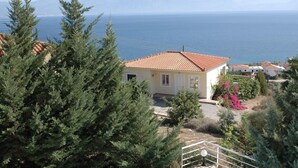 A coastal house with a tiled roof, surrounded by greenery and a clear view of the sea. - Villa Thalia in Pilos Nestor (Messini)