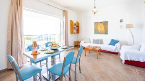 A bright living room with a dining area, white furniture, and a painting on the wall. - Villa Thalia in Pilos Nestor (Messini)