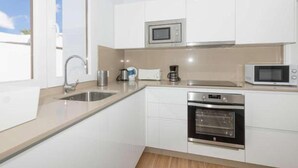 Una cocina moderna con armarios blancos, electrodomésticos de acero inoxidable y un amplio ventanal.