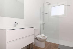 Un baño con lavamanos blanco, inodoro y cabina de ducha de vidrio.