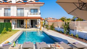 A two-story house with a swimming pool, outdoor seating, and a covered patio area. - Villa Lidya in Dalyan (Ortaca)